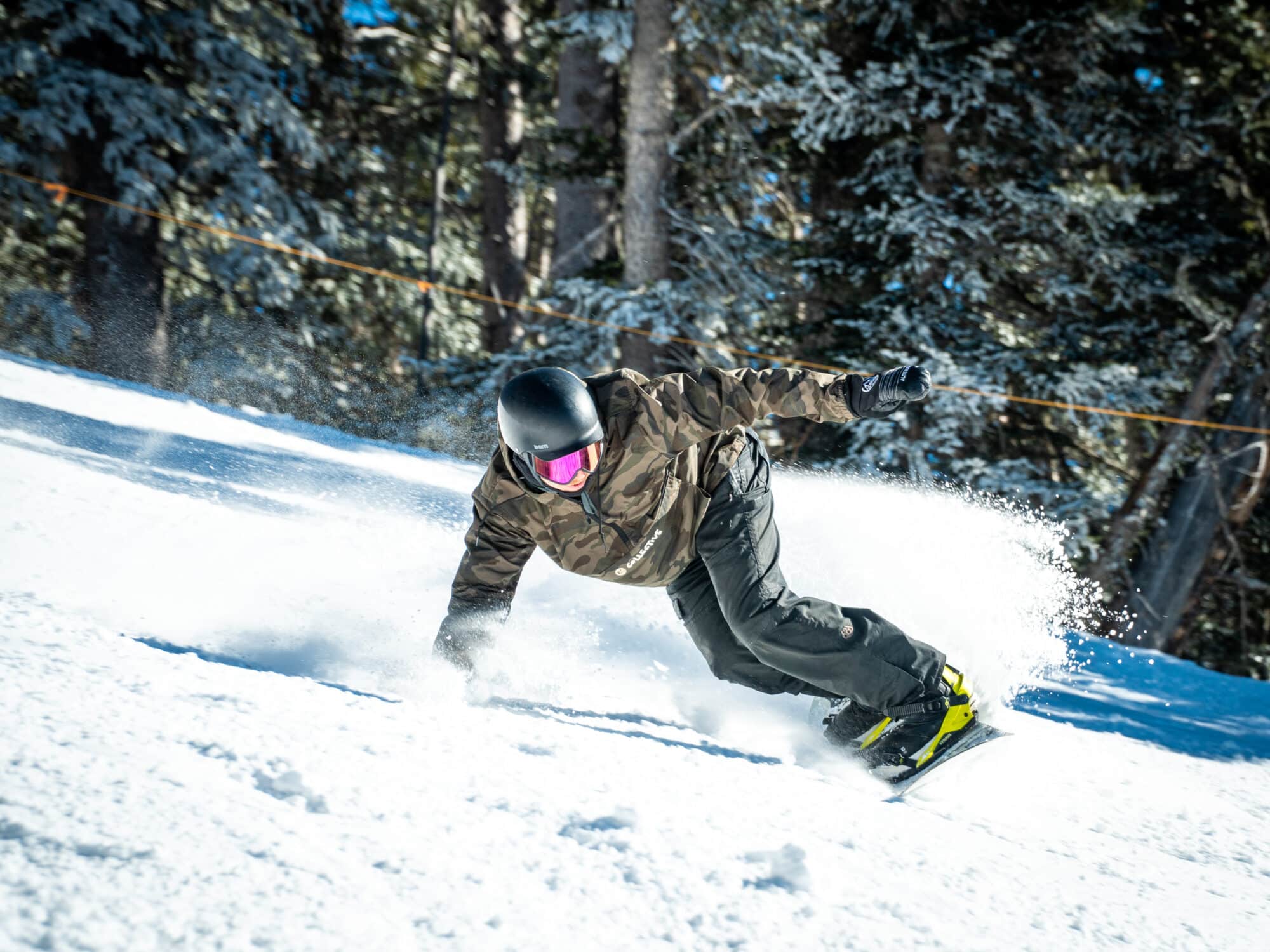 Male snowboarder slashing through snow.