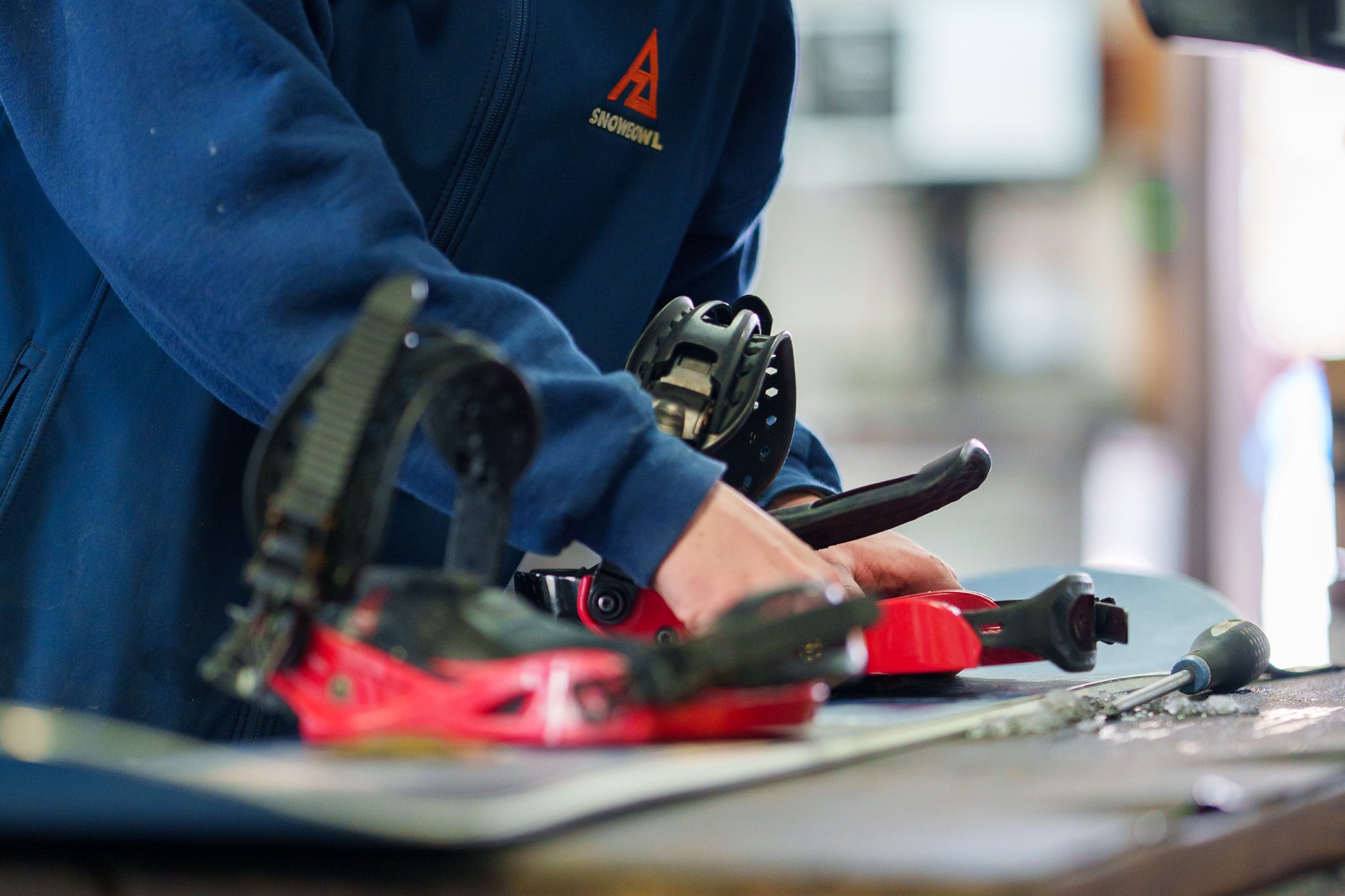 A Snowbowl employee adjusting bindings on a rental snowboard