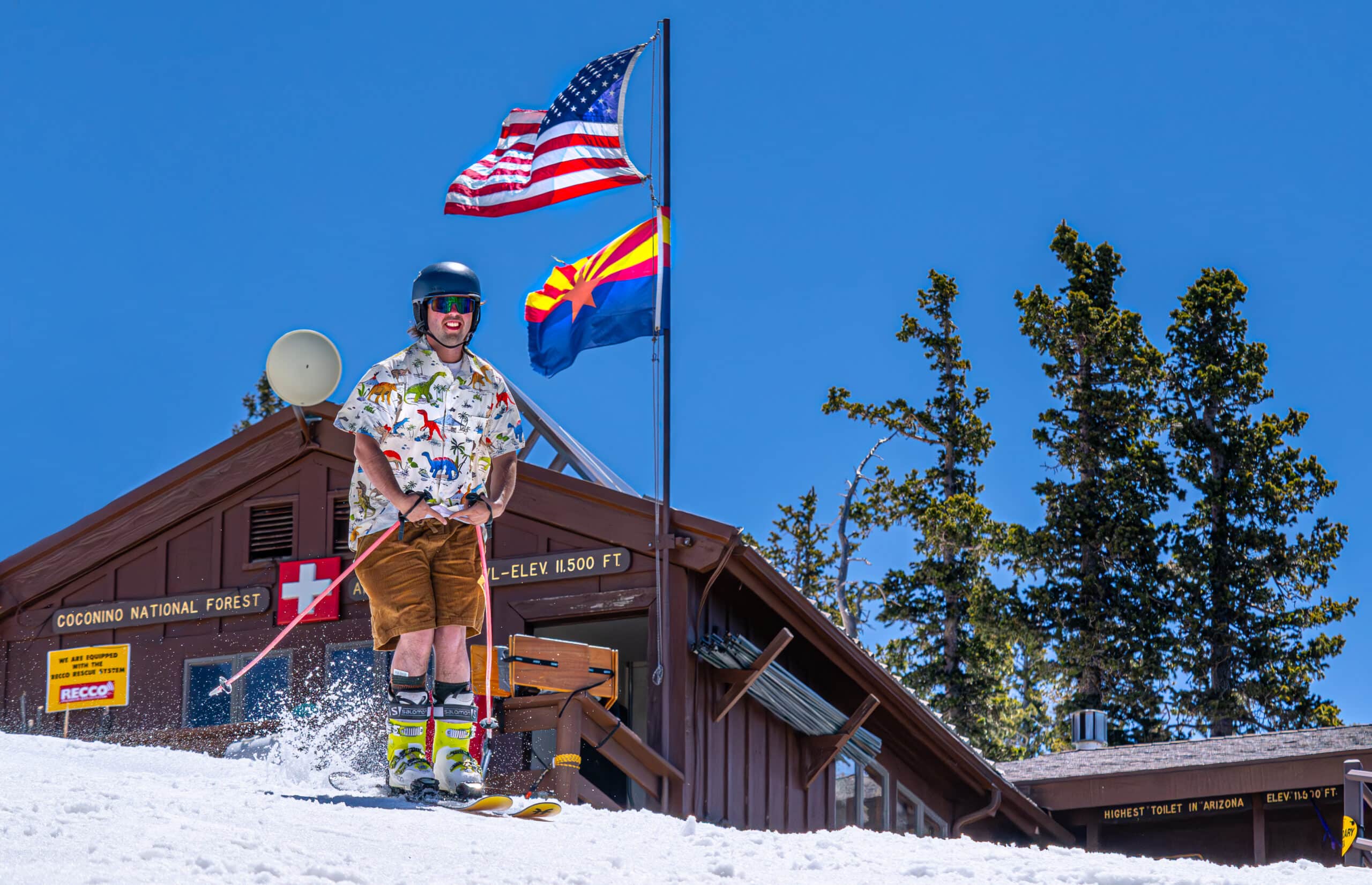 Skier in shorts with Arizona flag waving in the background