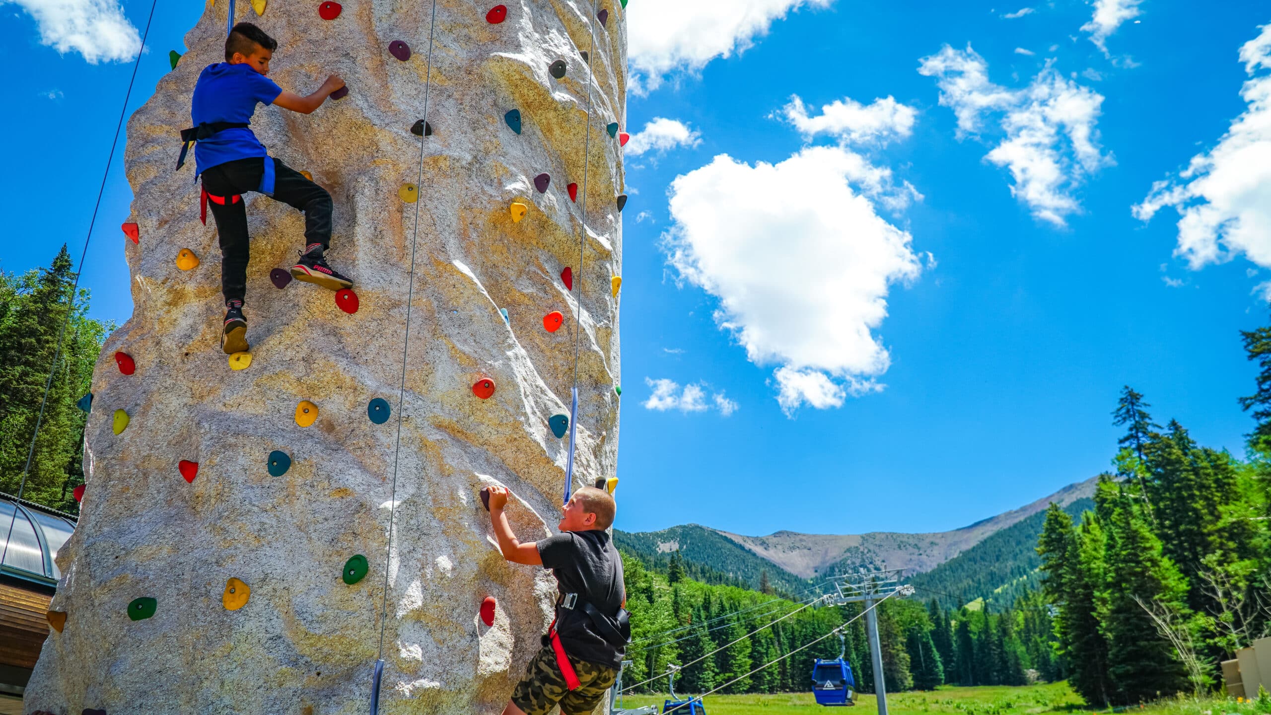 Two kids climbing the rock wall