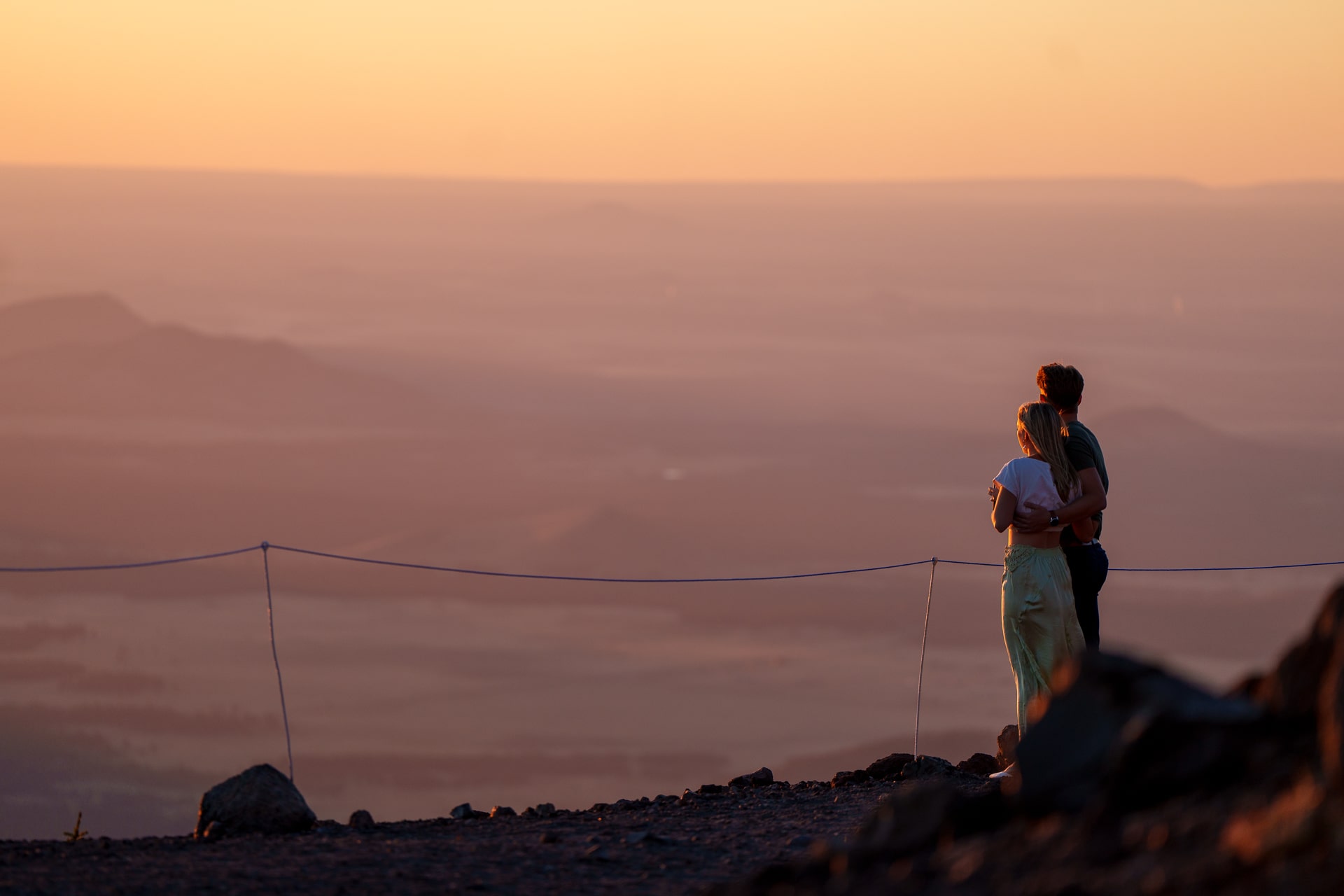 Couple looking off at a sunset landscape