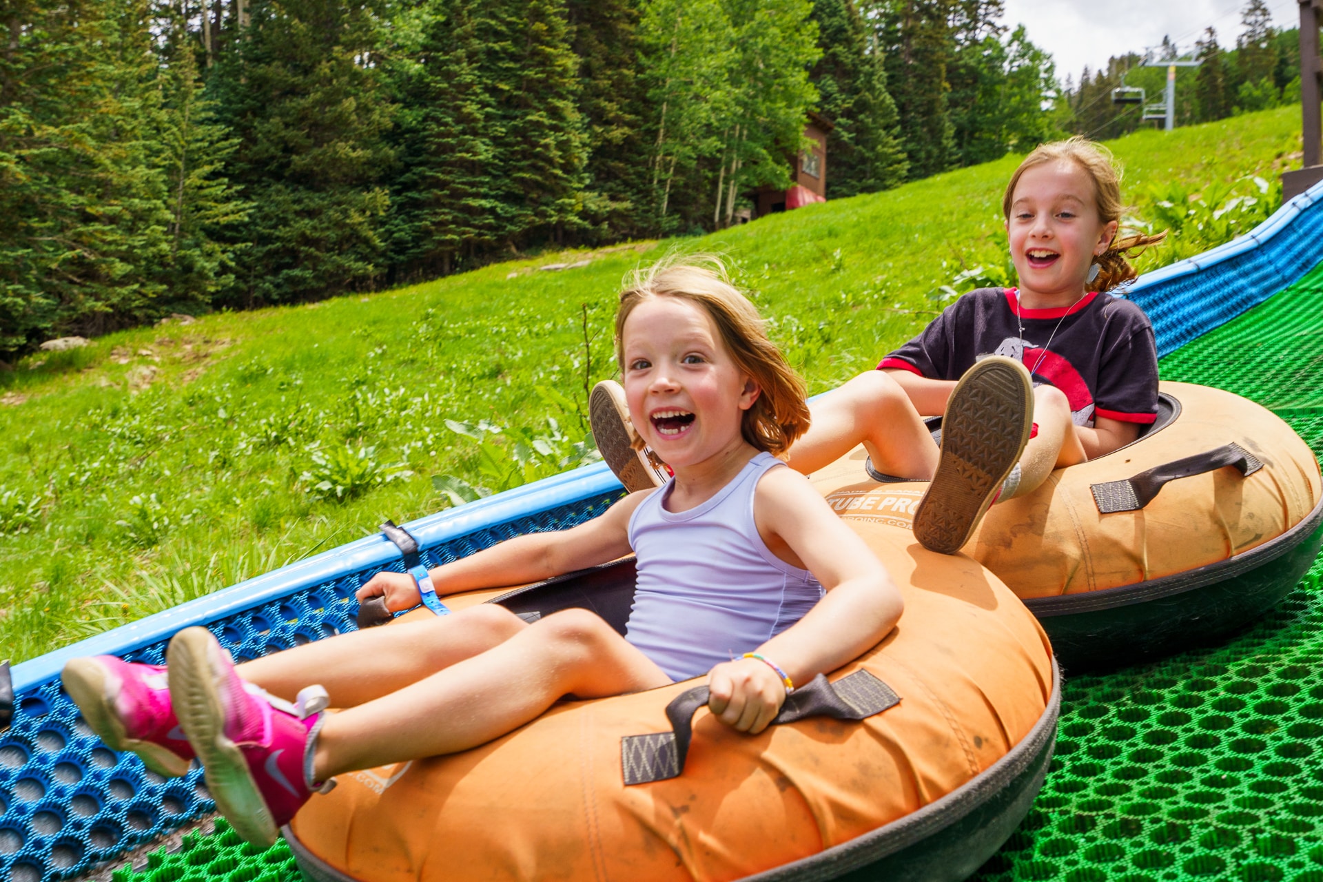 Two girls cheerfully riding down tubing hill