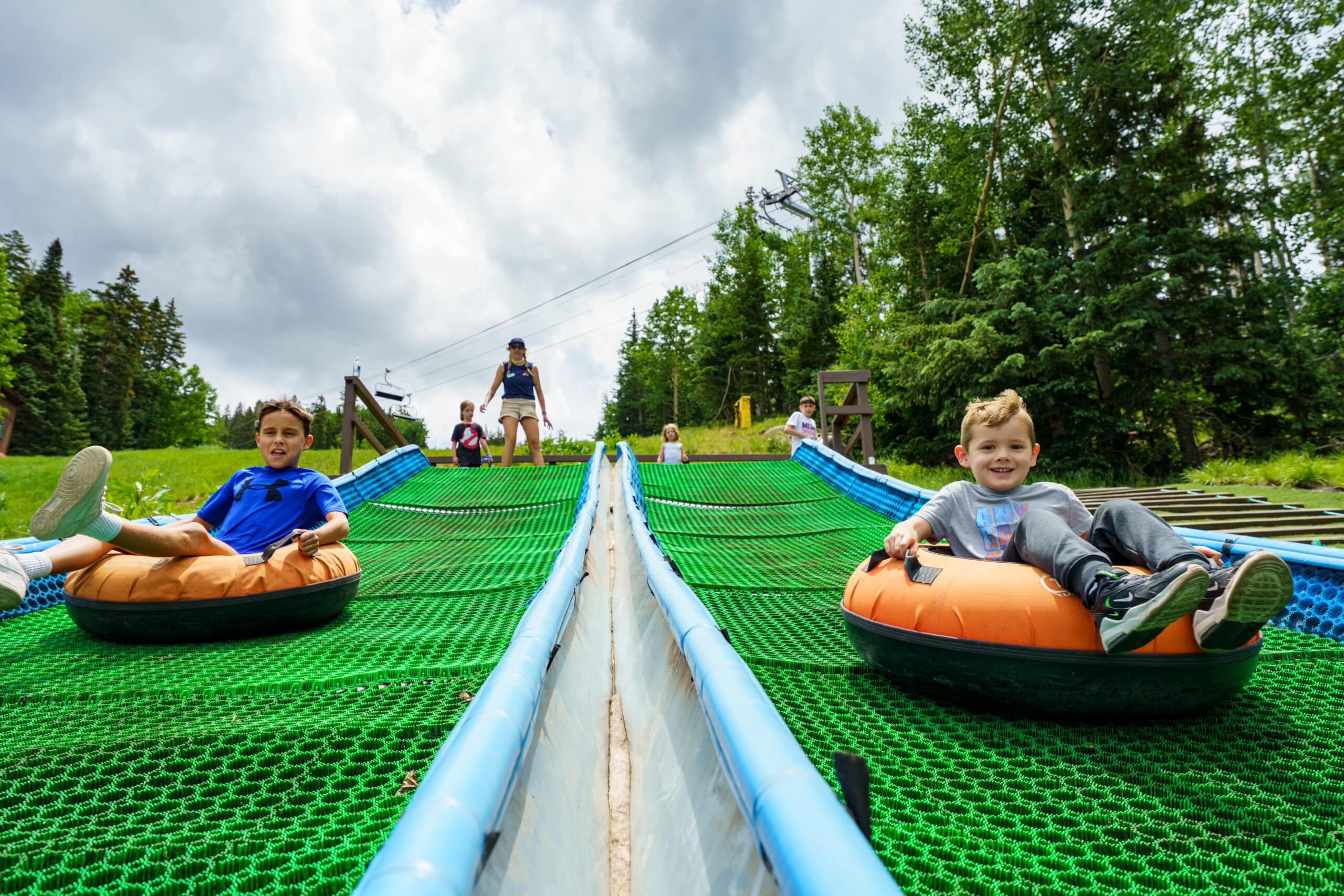 2 kids coming down the summer tubing hill