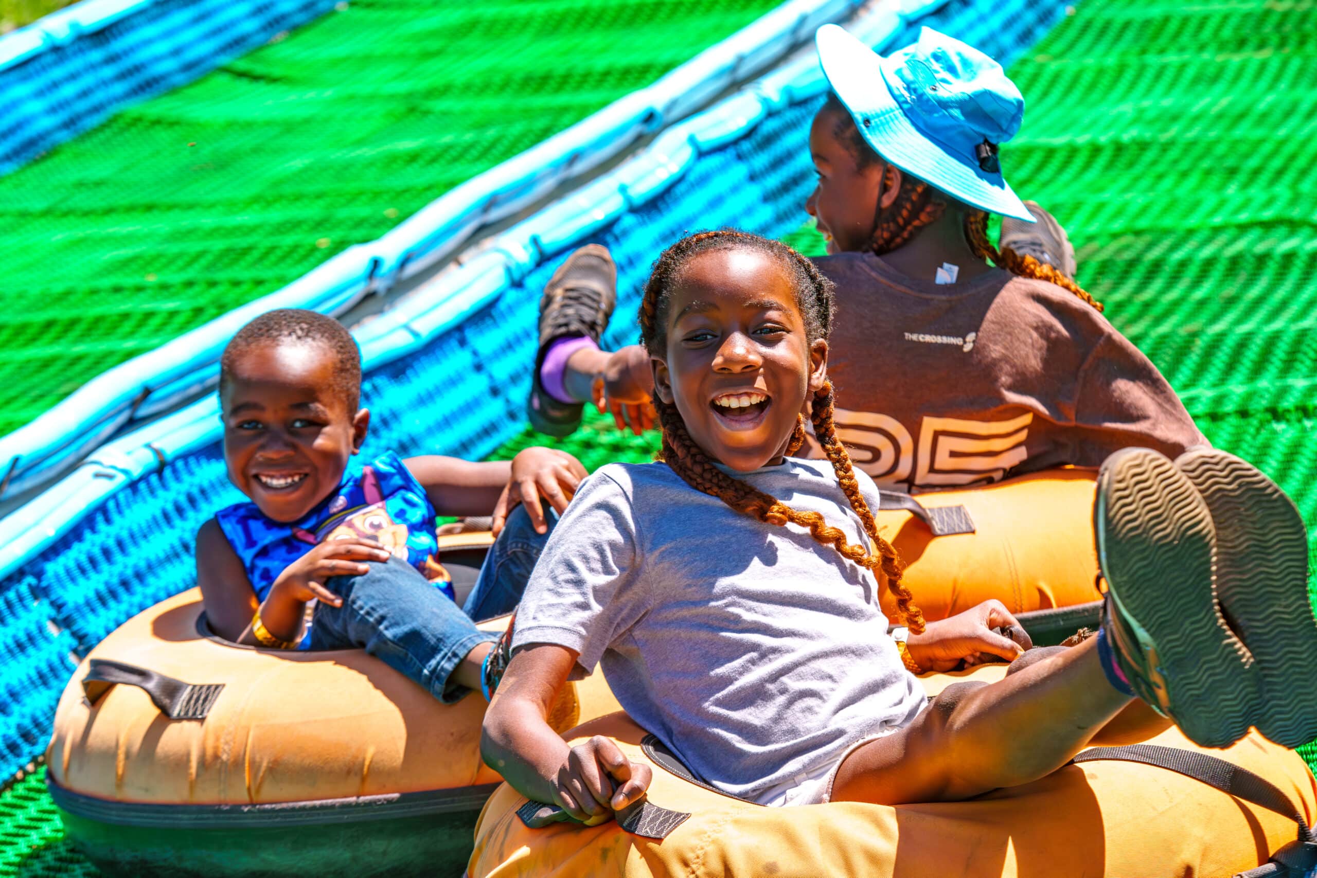 A group of kids coming down the summer tubing hill together.
