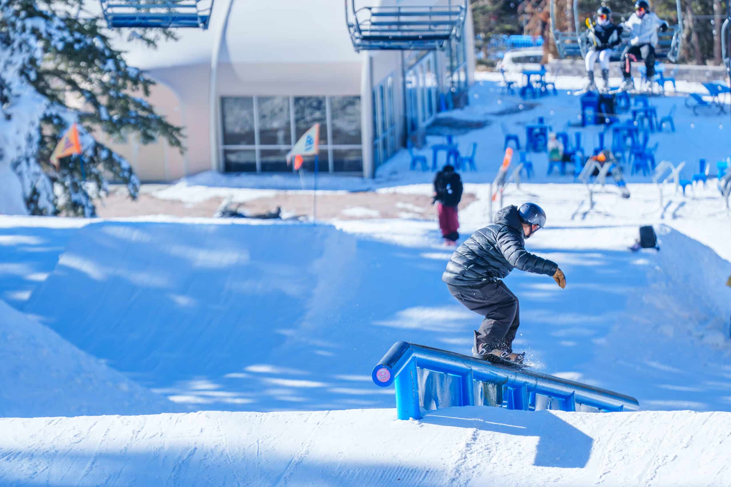 Snowboarder grinding a rail in the Sunset Terrain Park