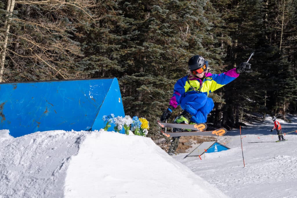 A little kid skiing a jump at a Sunset Terrain Park