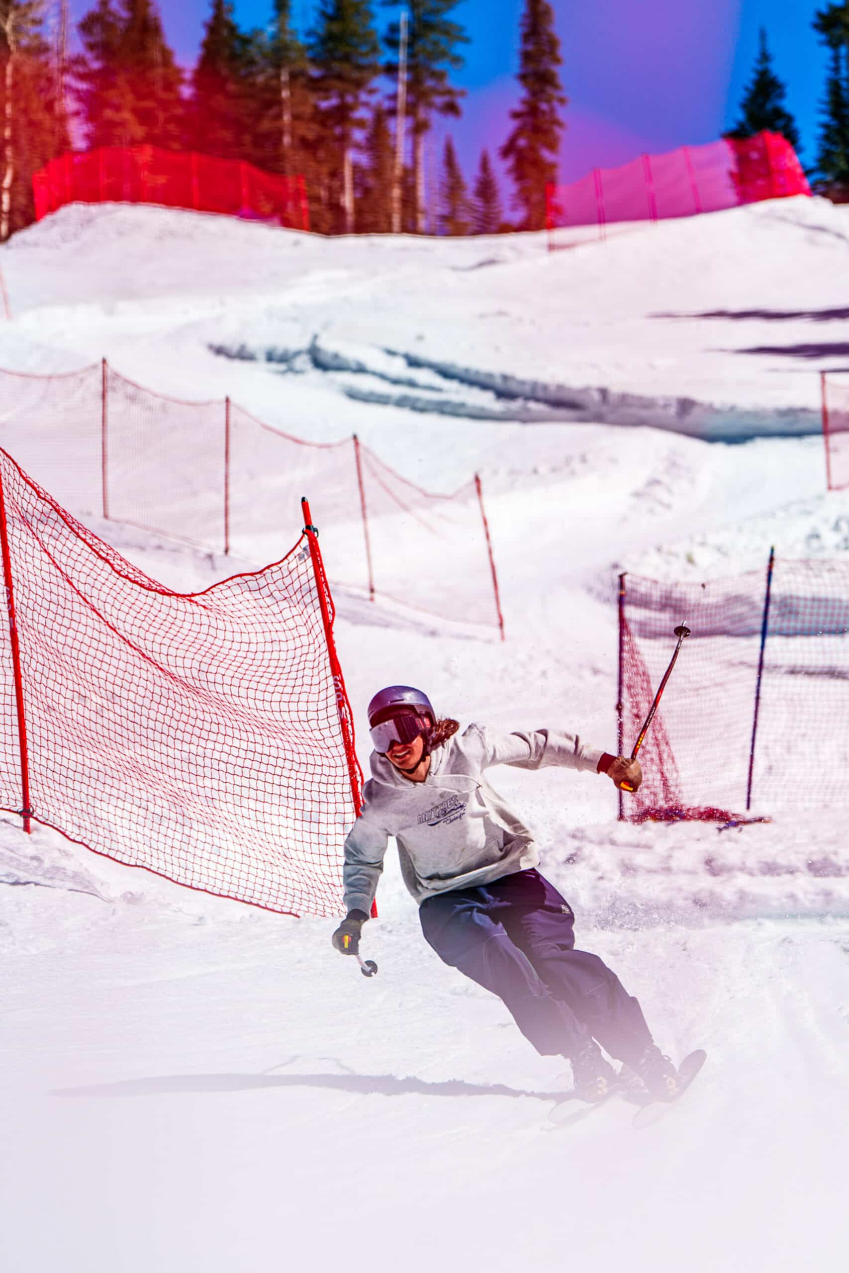 A skier in a hoodie coming down a slalom course at Snowbowl