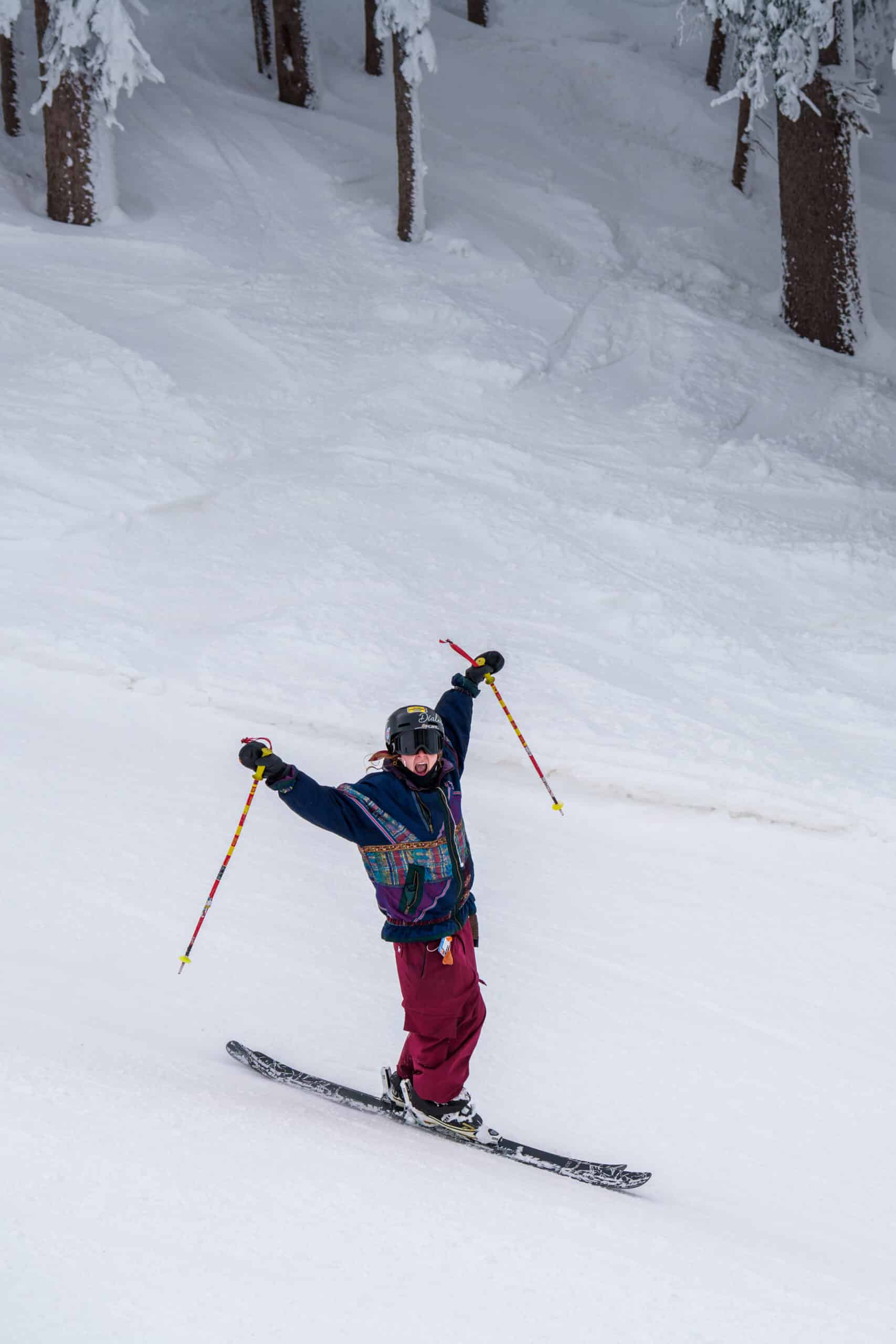 A skier holding their poles up going down a run at Snowbowl