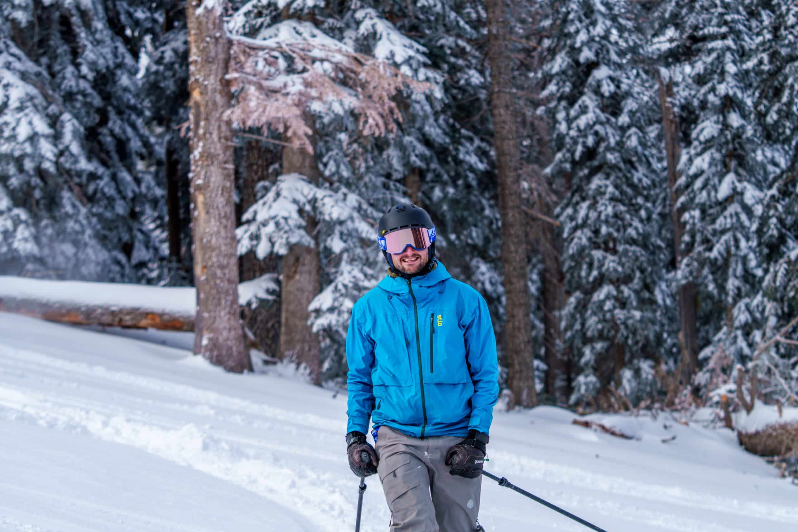 A skier in blue smiling on a powder day