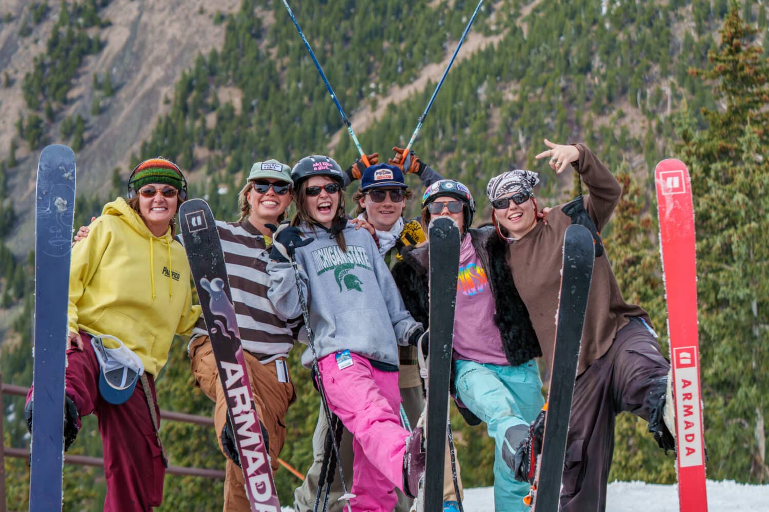 A group of skiers at the top of the Arizona Gondola each holding one ski out and smiling