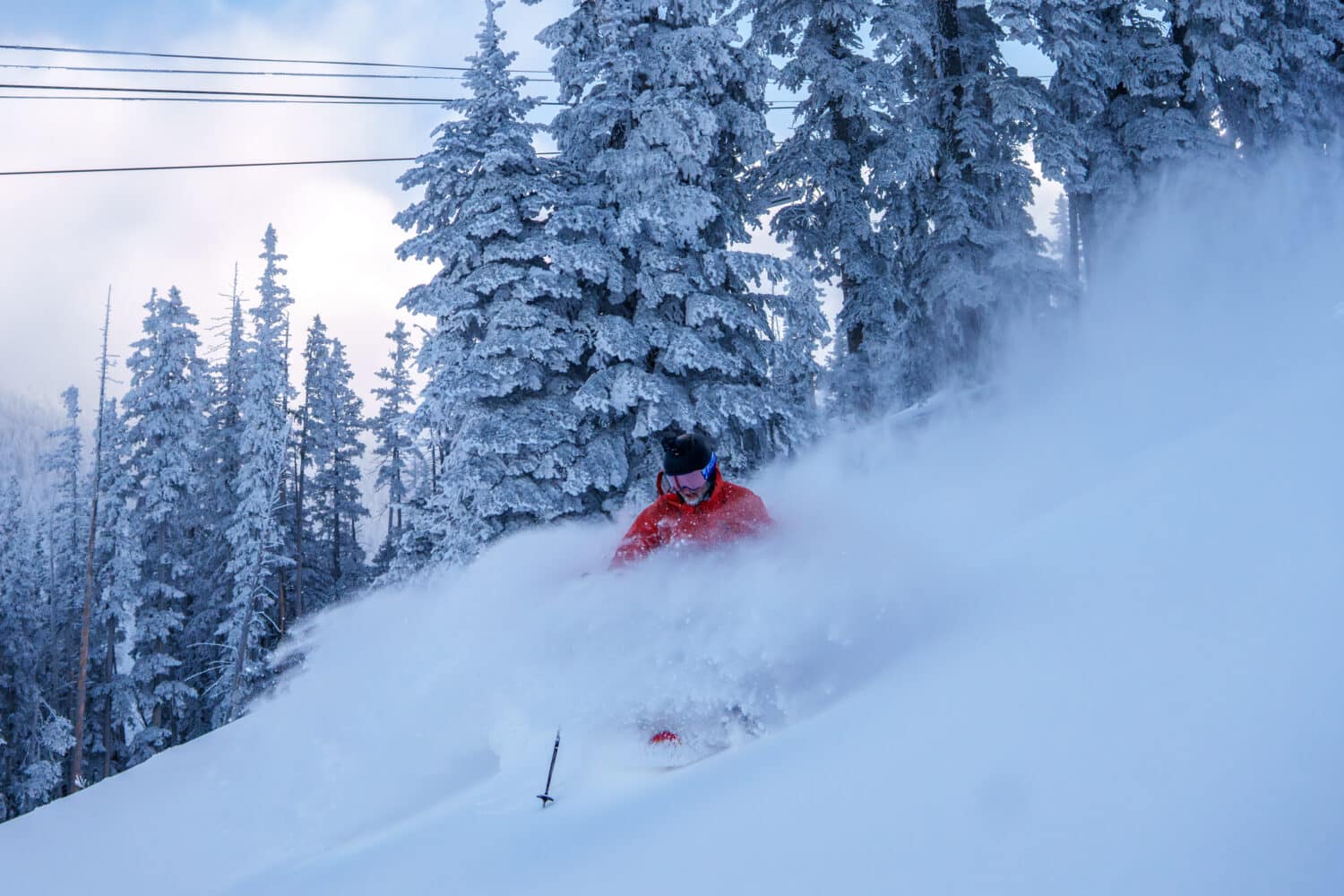 A skier at Snowbowl charging through powder