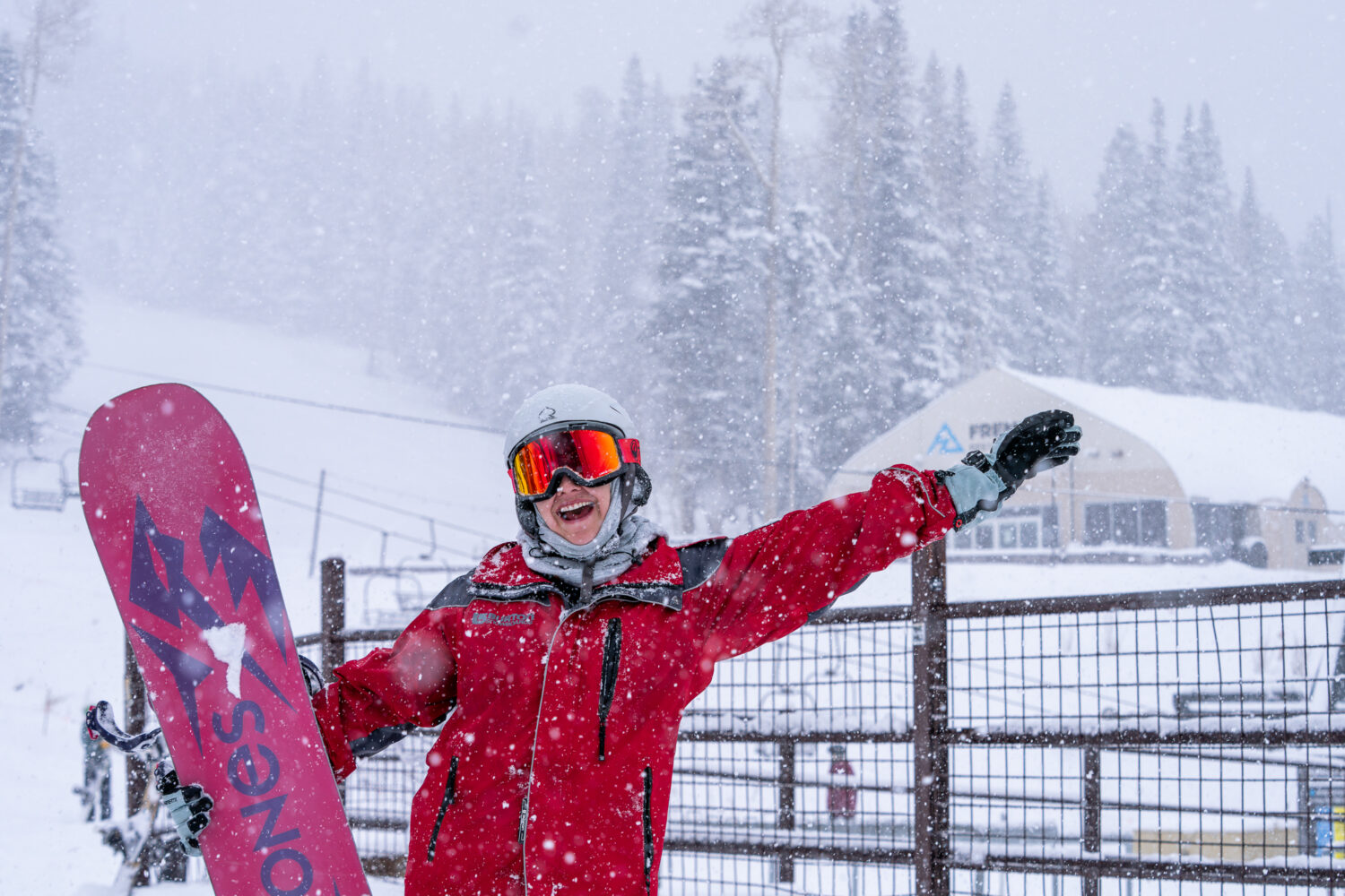 A snowboarder outside Hart Prairie lodge celebrating during a snow day