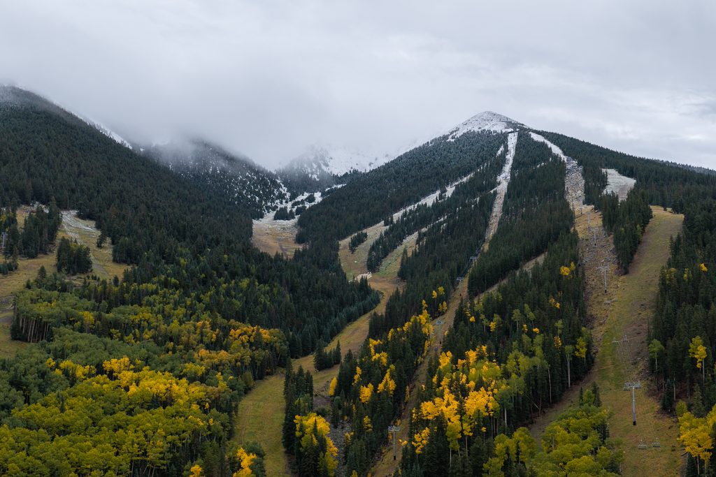 Aerial view of Snowbowl's fall yellow aspen trees and snowy white-capped summit