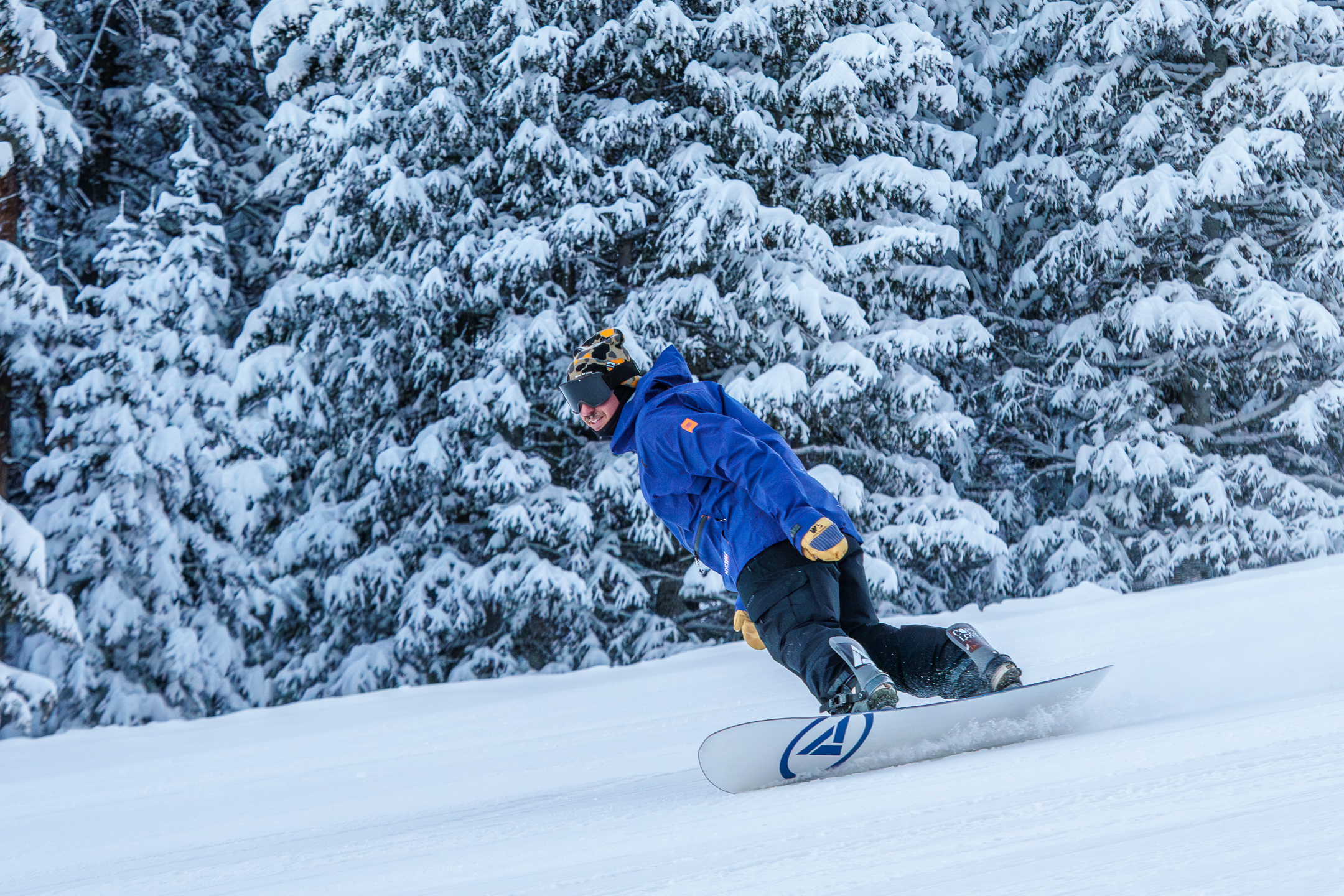 Snowboarder in blue coming down a run, smiling
