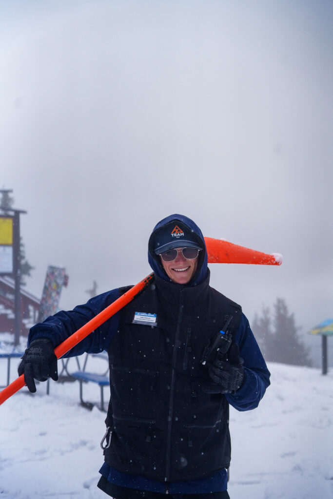 A lift operator at the top of the mountain with a snow shovel during first snowfall