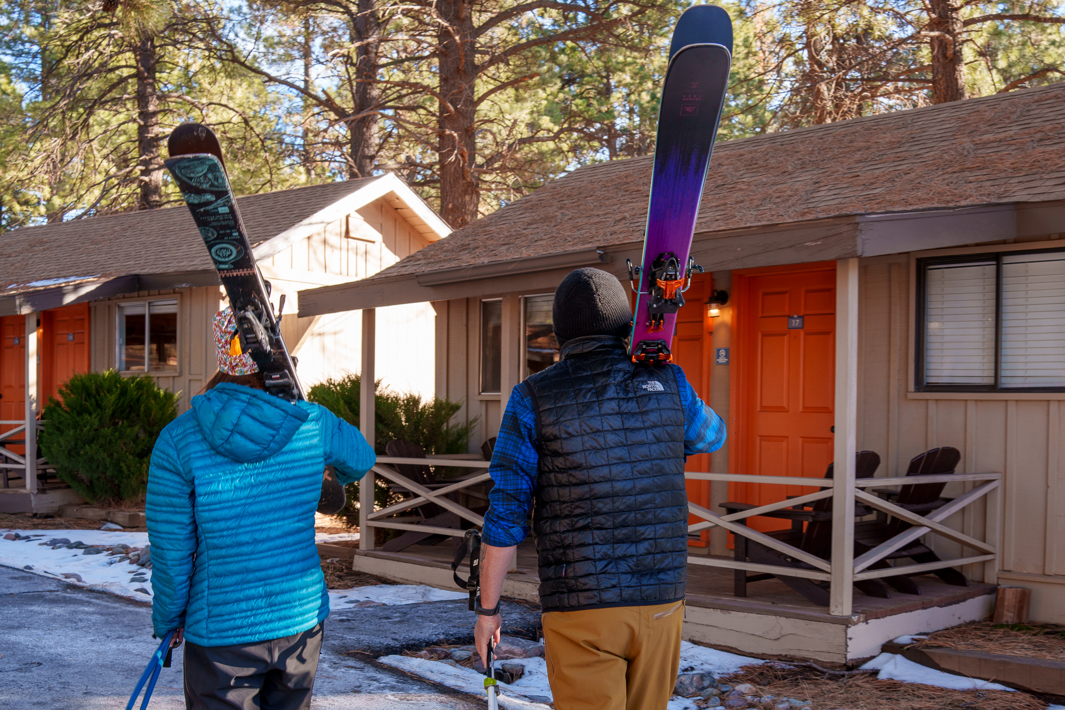 Two guests carrying their skis to their rooms in the snow